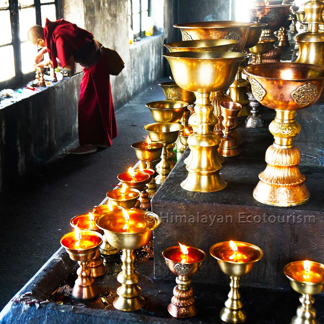 Un moine avec des lampes à beurre au Ladakh